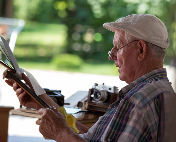Hombre mayor mirando fotos viejas — Foto de Stock