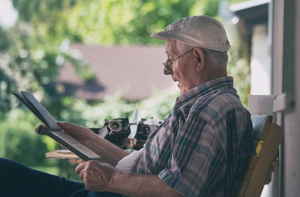 Senior schaut sich alte Fotos an — Stockfoto