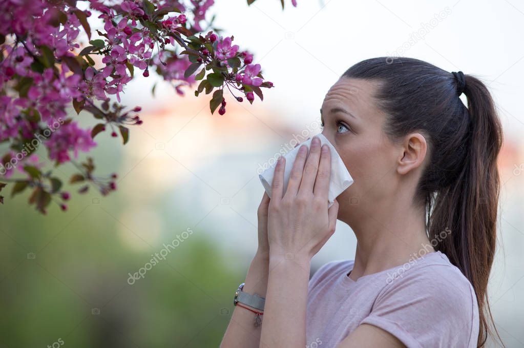 Woman blowing nose because of spring pollen allergy