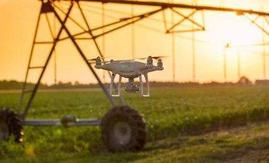 Gün batımında tarlada sulama sisteminin önünde uçan drone