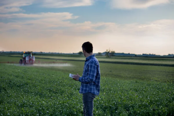 Fermier avec tablette et tracteur — Photo