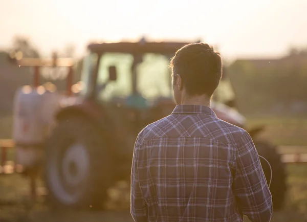 Farmer a traktor előtt a területen — Stock Fotó