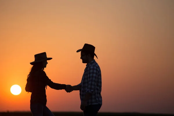 Boeren schudden handen bij zonsondergang — Stockfoto