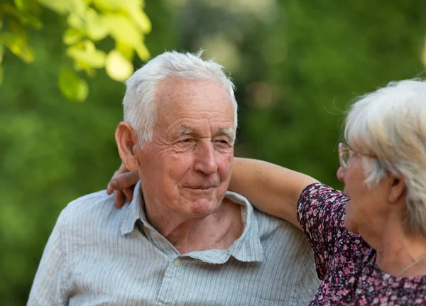 Пожилая пара обнимается в парке — стоковое фото