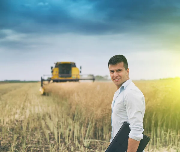 Businessman with laptop in front of combine harvester — Stock Photo, Image