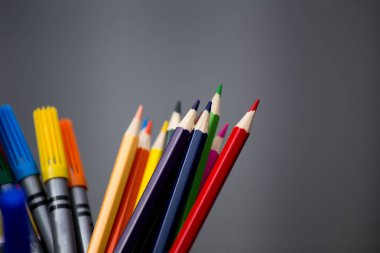 Gri arka plana karşı keçeli kalemler ve boya kalemleri