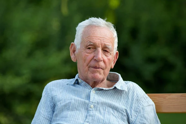 Oude man zittend in de tuin — Stockfoto