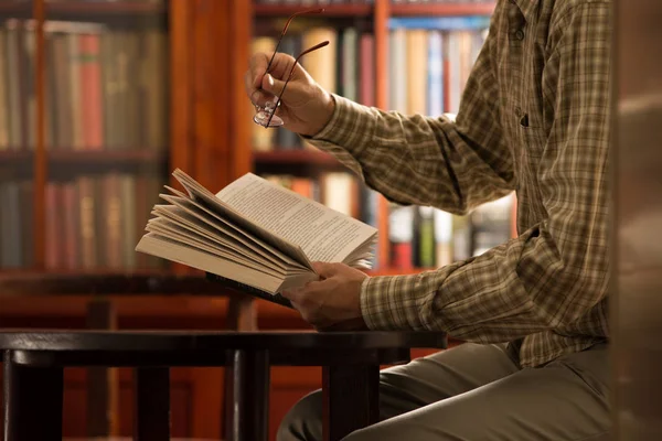 Mann liest Buch in Bibliothek — Stockfoto