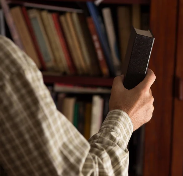 Man putting book on shelf — Stock Photo, Image