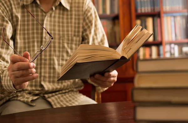 Человек читает книгу в библиотеке — стоковое фото