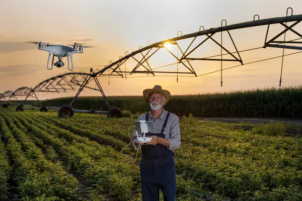 Rolnik z dronem w terenie z systemem nawadniania — Zdjęcie stockowe