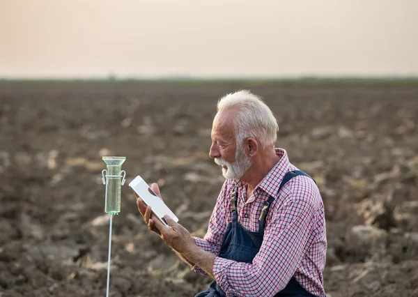 Boer naast regen gauge in veld — Stockfoto