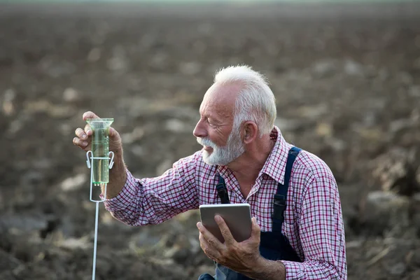 Agricultor junto a medidor de lluvia en campo — Foto de Stock