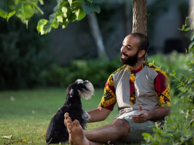 Çimenlerin üzerinde oturan insan ve köpek