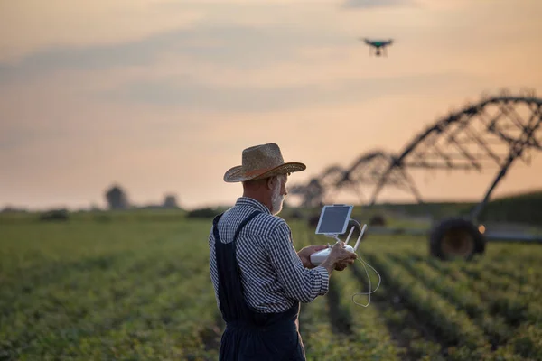 Rolnik z dronem w terenie z systemem nawadniania — Zdjęcie stockowe