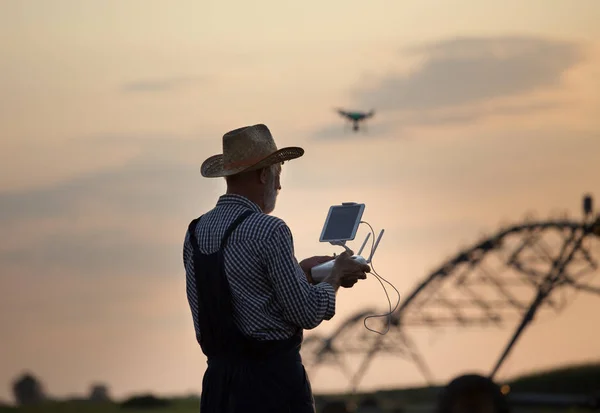 Rolnik z dronem w terenie z systemem nawadniania — Zdjęcie stockowe