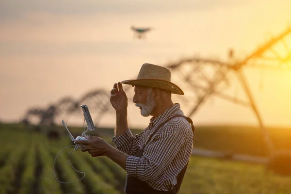 Agricoltore con drone in campo con impianto di irrigazione — Foto Stock