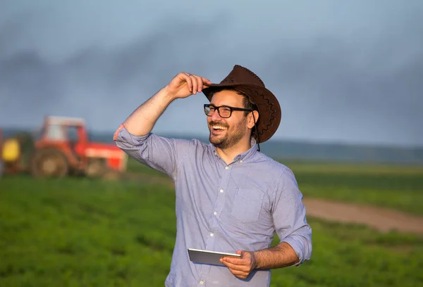 Agricultor com tablet na frente do trator no campo — Fotografia de Stock