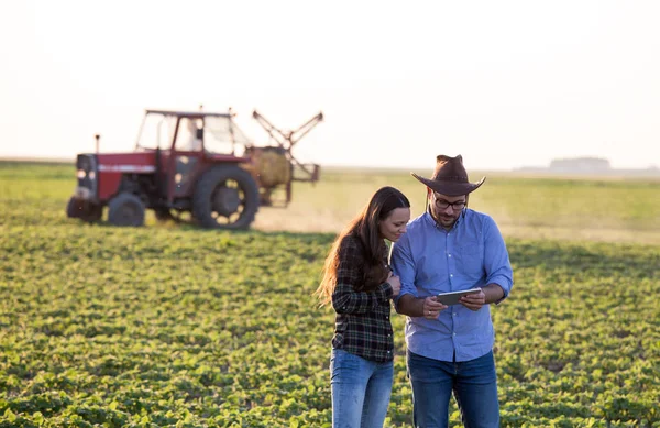 Agricultores con tableta delante del tractor en campo — Foto de Stock