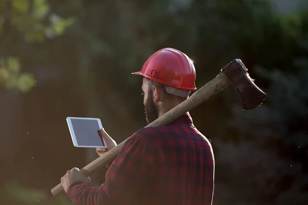 Lumberjack com machado, capacete e tablet — Fotografia de Stock