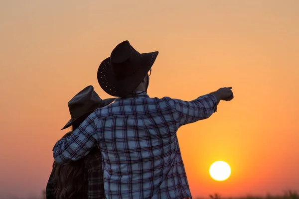 Pareja mirando la puesta de sol en el campo — Foto de Stock