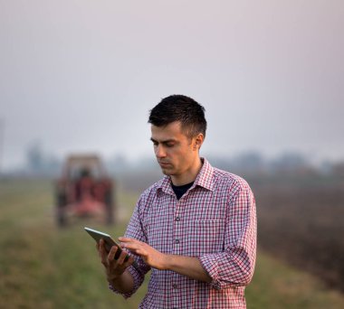 Traktörün önünde tabletli çiftçi