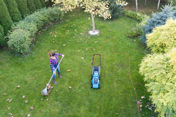 Wanita menyapu daun dan memotong rumput — Stok Foto