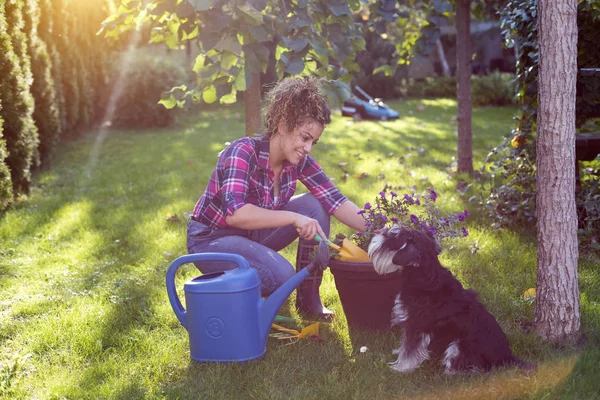 Niña y perro cuidando plantas en el jardín — Foto de Stock