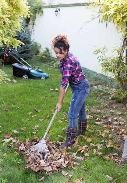 Mujer rastrillando hojas en el césped — Foto de Stock