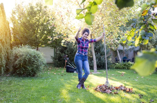 Frau harkt Laub im Garten — Stockfoto