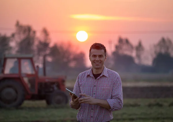 Agricultor com tablet na frente do trator — Fotografia de Stock