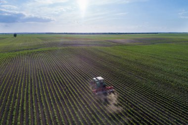 İlkbahar zamanı soya fasulyesi tarlasını yıkan traktörün hava görüntüsü