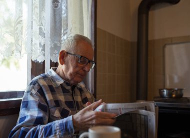 Gözlüklü son sınıf öğrencisi evdeki eski moda iç mekanlarda gazete okuyor.