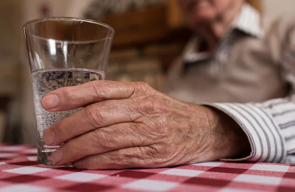 靠近老人的手 拿着杯子在餐桌边喝水 — 图库照片