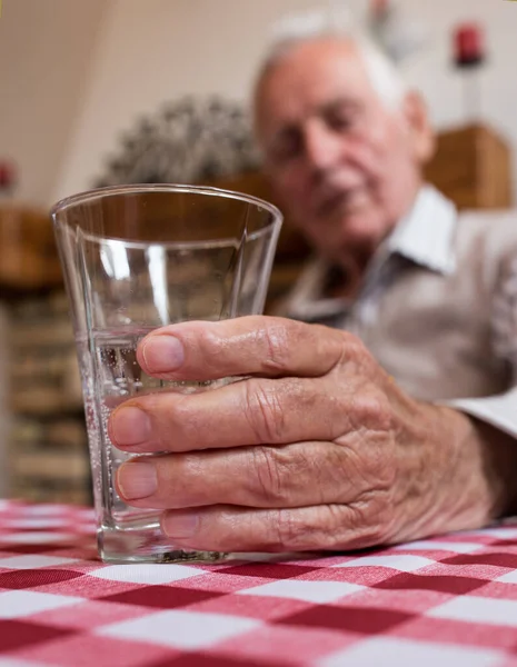 靠近老人的手 拿着杯子在餐桌边喝水 — 图库照片