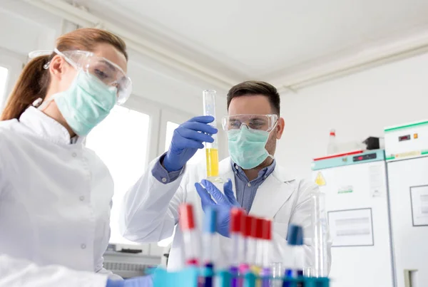 两名生物学家在实验室测试玻璃瓶中的一些化学品 — 图库照片