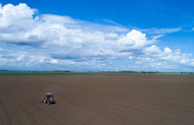 Aerial image of tractor harrowing field in spring time shoot from drone clipart