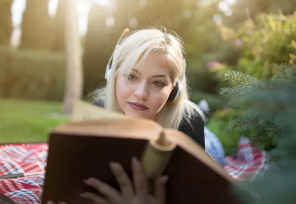 Teenagermädchen Mit Kopfhörern Auf Dem Bauch Und Lesebuch Auf Decke — Stockfoto