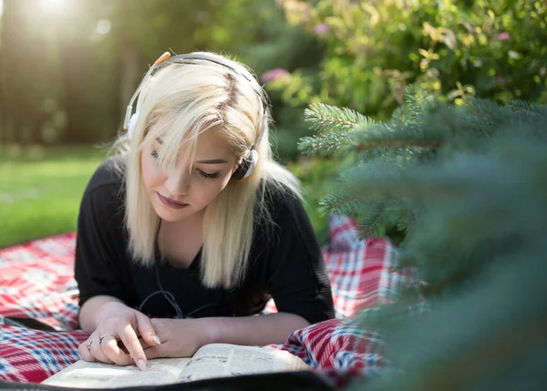 Nastolatka Słuchawkami Leżącymi Brzuchu Książką Kocu Parku Okresie Letnim — Zdjęcie stockowe