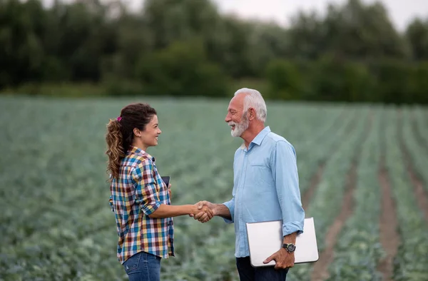 農場で握手をするシニア農家と若い女性 — ストック写真