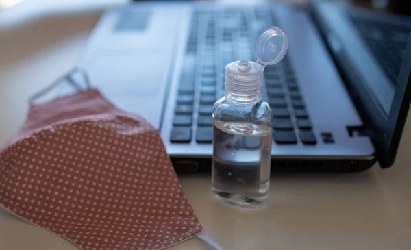 Sluiten Van Beschermende Stof Masker Desinfecterende Fles Voorkant Van Laptop — Stockfoto