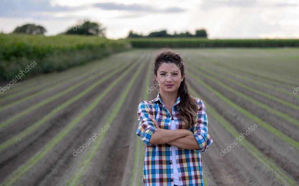 Portrait of confident and satisfied farmer woman standing with crossed arms in agricultural field