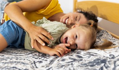 Anne ve küçük kızı, sıcak evlerinde yataklarında uzanıp, öğleden sonraları keyifli bir bağ kurarak kahkahalarını paylaşıyorlar..