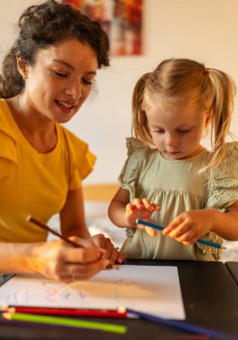 Anne ve genç kızı, gece boyunca doğal ışık ve konforlu ortamlarla çevrili, yaratıcı çizim seanslarına katılıyorlar.