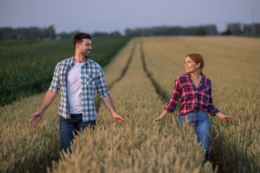 Çiftçi çift tarlada birbirlerine bakıp gülümsüyor. Birbirlerine ellerini uzattıklarında aralarında bir sıra altın buğdayla traktör işaretlerinde yürürler.