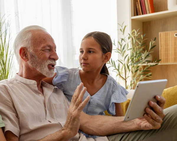 Üst düzey bir adam, genç bir kızla samimi oturma odasındaki dijital cihazda içeriği keşfederken canlı sohbete dalıyor.