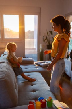 Neşesiz genç bir kadın somurtkan kızını güneş batarken yatmaya ikna etmeye çalışıyor.