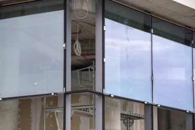 Installing large size glass windows to a multi commercial office building. clipart