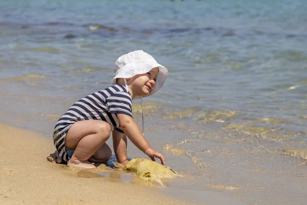 Niño en la playa jugando con piedra grande, concepto de los niños —  Fotos de Stock