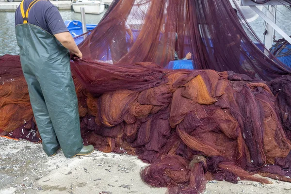 Pescador limpiando redes y extendiéndose por el suelo —  Fotos de Stock